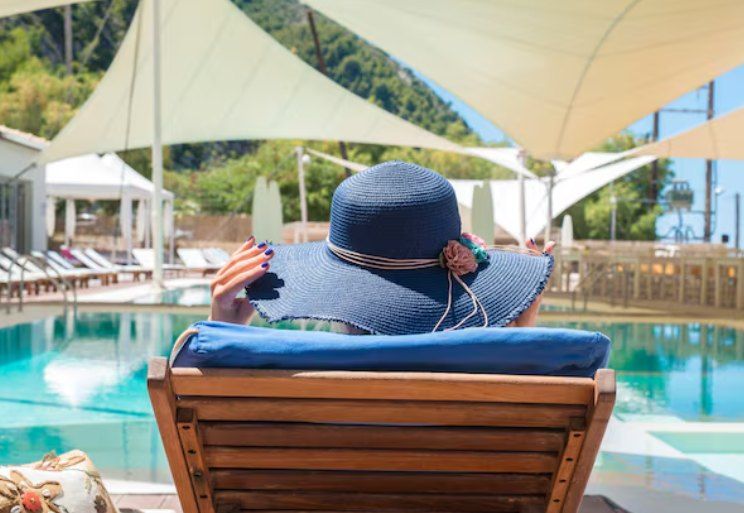 Mujer con sombrero descansando junto a una piscina durante una escapada
