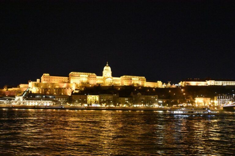El castillo de Buda iluminado reflejado en el Danubio